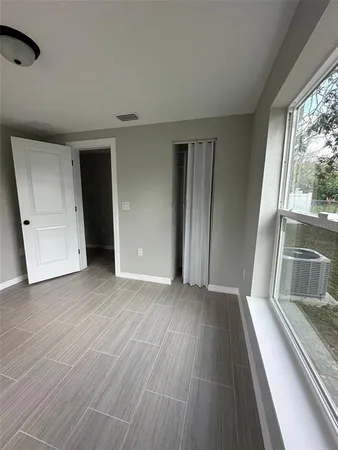 a view of an empty room with wooden floor and a window