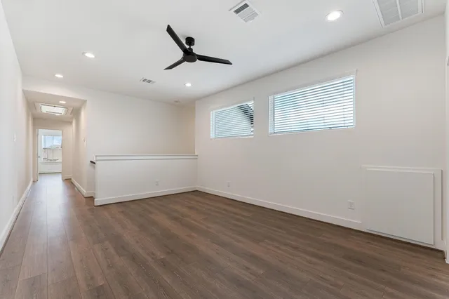 a view of a livingroom with wooden floor a ceiling fan and windows