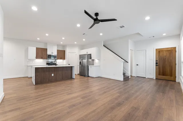 a living room with stainless steel appliances kitchen island hardwood floor and a sink