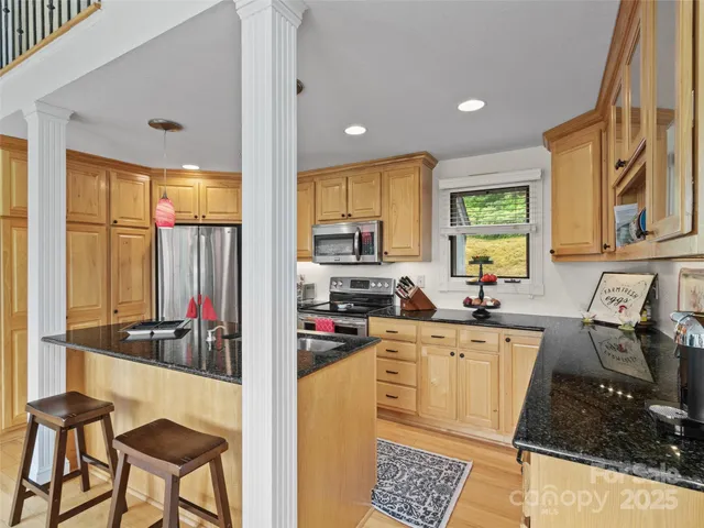 a kitchen with stainless steel appliances granite countertop a stove a sink and a refrigerator with wooden floor