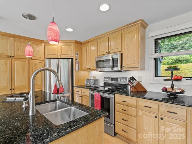 a kitchen with kitchen island granite countertop a sink stainless steel appliances and cabinets