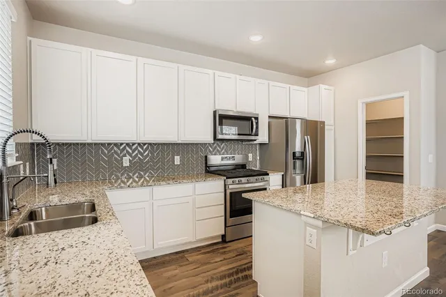 a kitchen with stainless steel appliances granite countertop a sink stove microwave and refrigerator