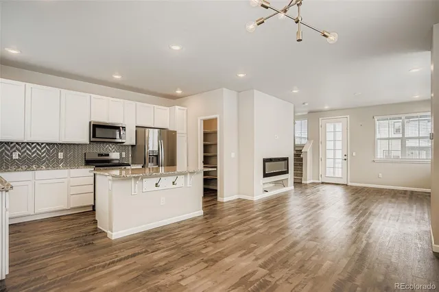 a kitchen with stainless steel appliances granite countertop a sink stove microwave and refrigerator