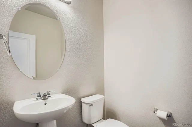 a bathroom with a toilet a sink and mirror