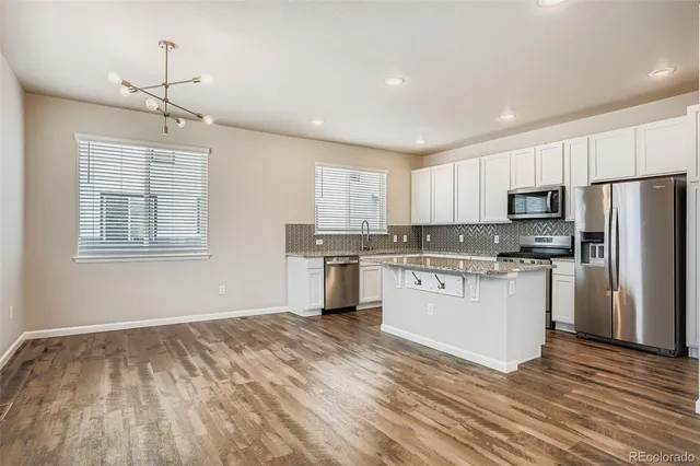 a kitchen with granite countertop white cabinets and stainless steel appliances