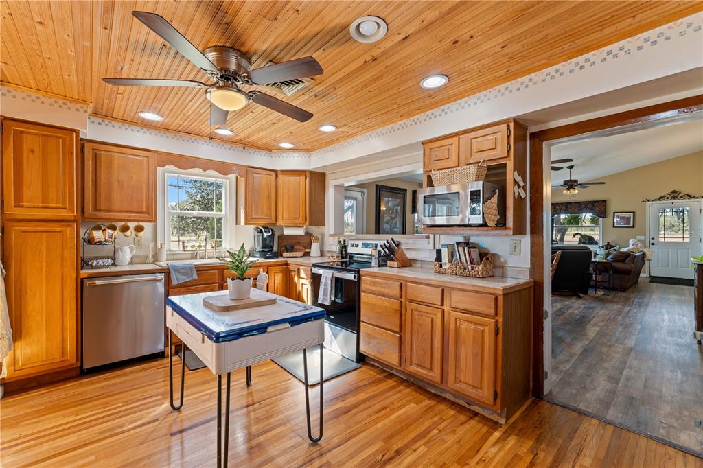 9504 Fort King Road Dade City, FL 33525 - Photo 10 of 14 a kitchen with stainless steel appliances granite countertop a refrigerator a sink dishwasher a stove and white countertops with wooden floor