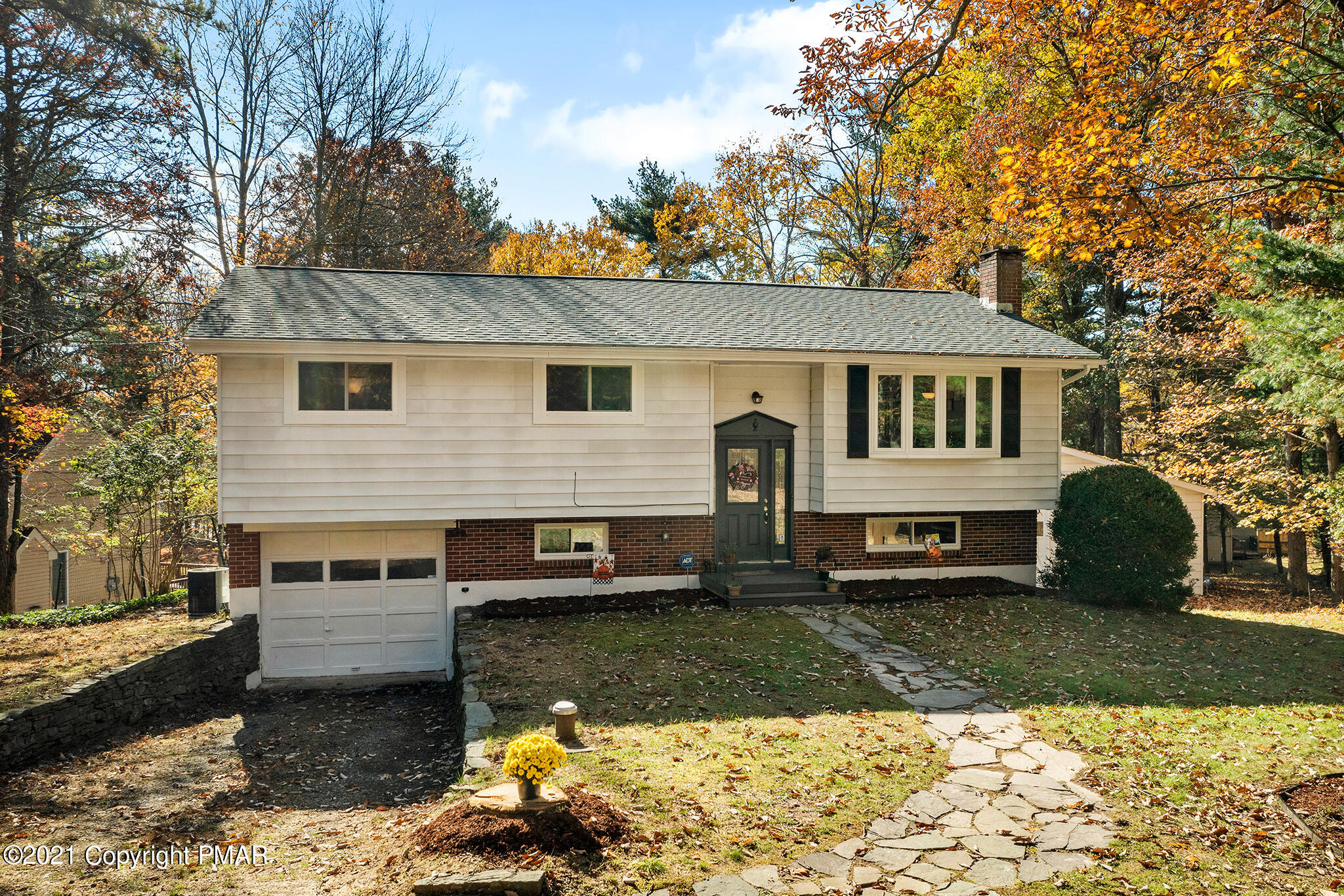 a view of a house with a yard chairs and large tree