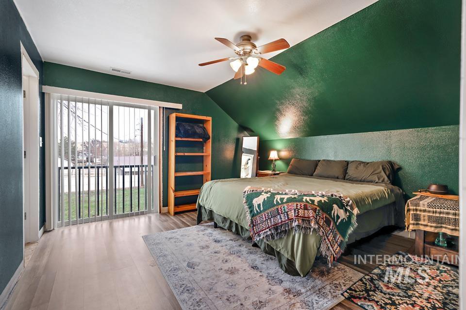 1230 East Main Street Weiser, ID 83672 - Photo 16 of 25 Bedroom featuring access to exterior, a textured wall, wood finished floors, vaulted ceiling, and ceiling fan