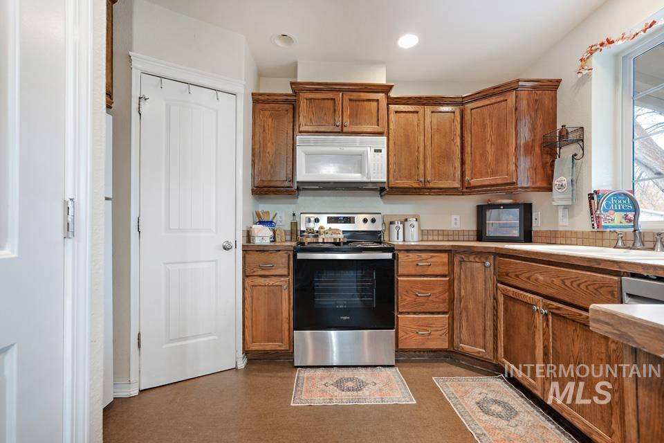 1230 East Main Street Weiser, ID 83672 - Photo 7 of 25 Kitchen featuring stainless steel range with electric stovetop, brown cabinets, white microwave, recessed lighting, and light countertops