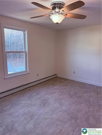 an empty room with a chandelier fan and windows