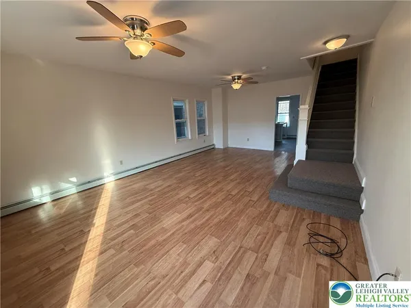 a view of empty room with wooden floor and fan