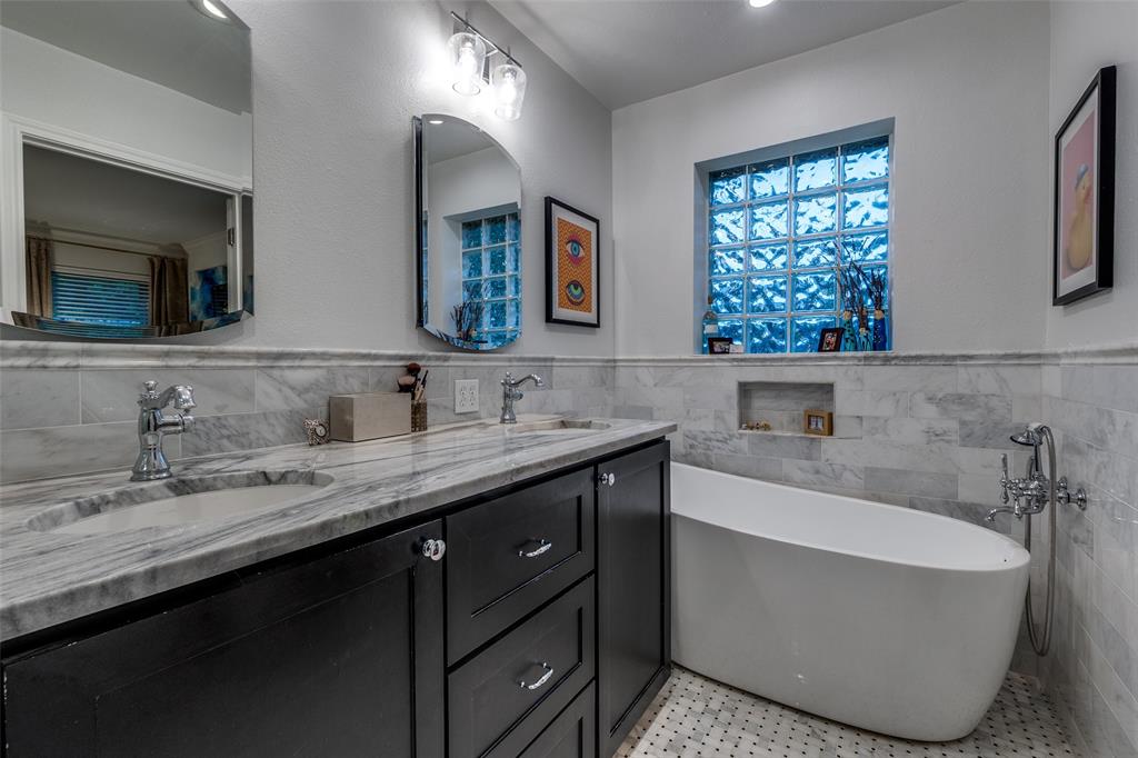 4159 Clover Lane Dallas, TX 75220 - Photo 17 of 25 Full bath with tile walls, double vanity, a freestanding bath, and wainscoting