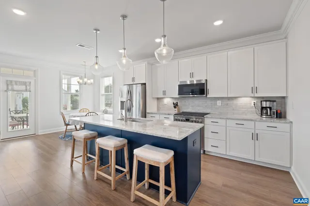 a kitchen with kitchen island granite countertop a table chairs sink and cabinets