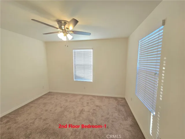 an empty room with a window and a fan