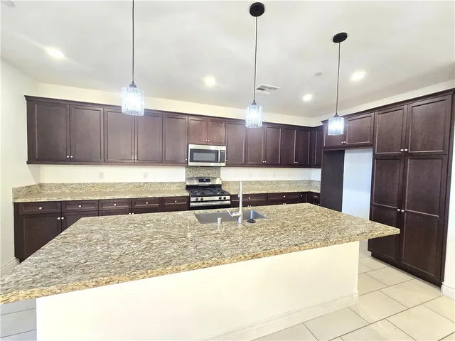 a large kitchen with granite countertop a sink counter top space appliances and cabinets