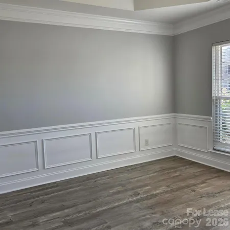 a view of an empty room with wooden floor and cabinet