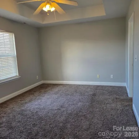 a view of a big room with window and chandelier fan