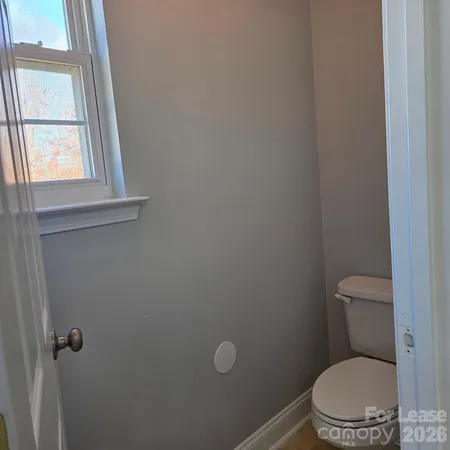 a white toilet sitting in a bathroom next to a window