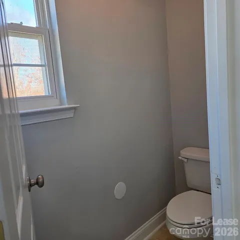 a white toilet sitting in a bathroom next to a window
