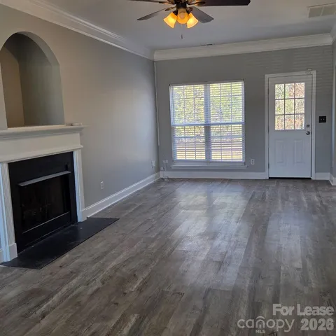 an empty room with wooden floor fireplace and windows