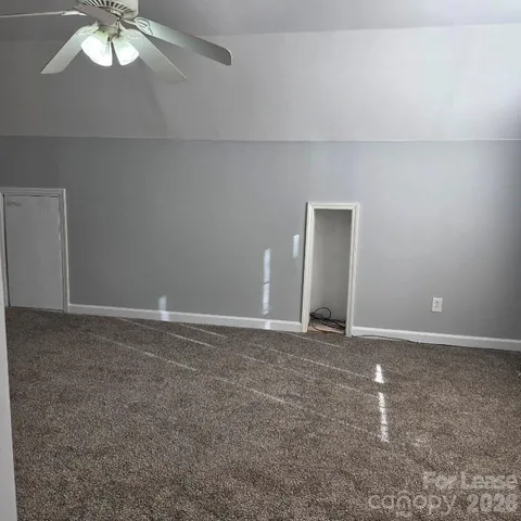 a view of an empty room with a chandelier fan