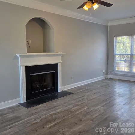 an empty room with wooden floor a fireplace and window