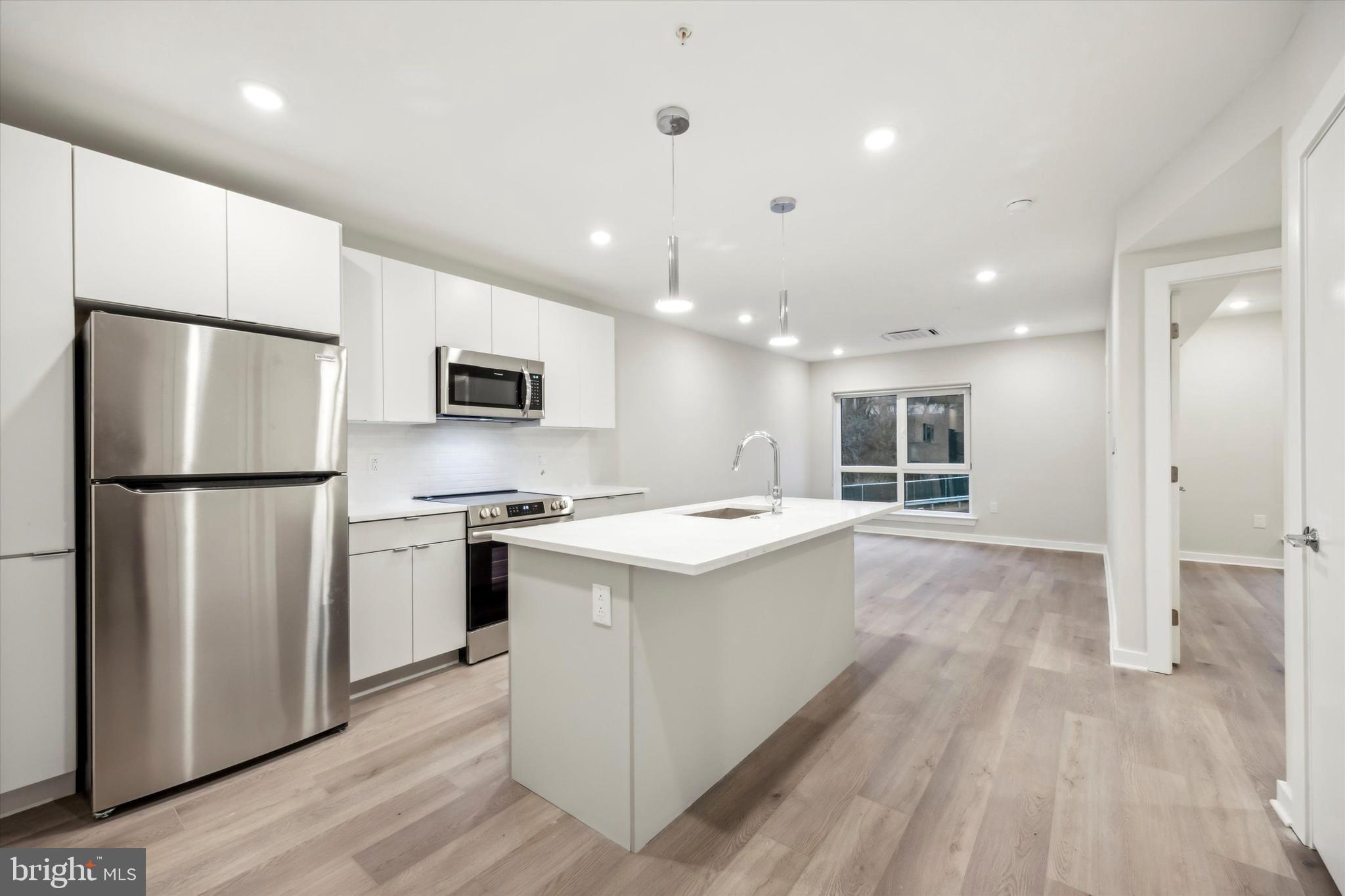 3449 Scotts Lane, Unit B309 Philadelphia, PA 19129 - Photo 1 of 6 a kitchen with stainless steel appliances granite countertop a refrigerator a stove a sink dishwasher and a refrigerator with wooden floor