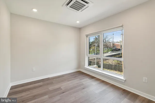 an empty room with wooden floor and windows