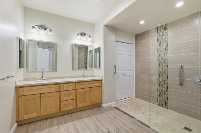 a spacious bathroom with a double vanity sink mirror and shower