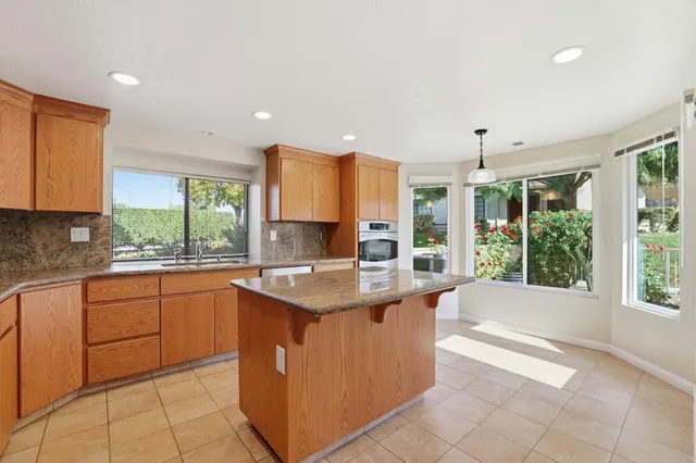 a large kitchen with stainless steel appliances granite countertop a stove a sink and a microwave