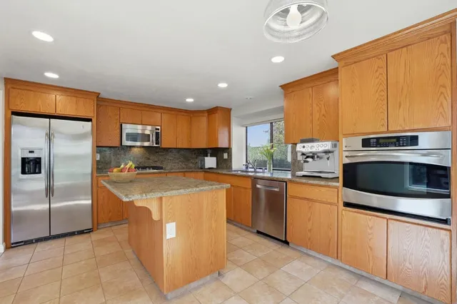 a kitchen with stainless steel appliances granite countertop a stove a sink and a refrigerator