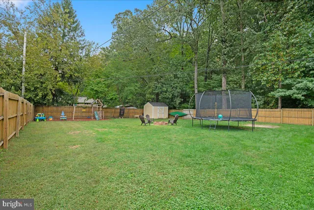 a view of a backyard with a slide trees and wooden fence