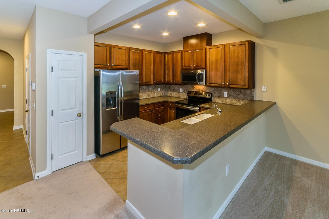 12991 Spring Rain Road Jacksonville, FL 32258 - Photo 7 of 23 a kitchen that has a sink a refrigerator and a stove top oven