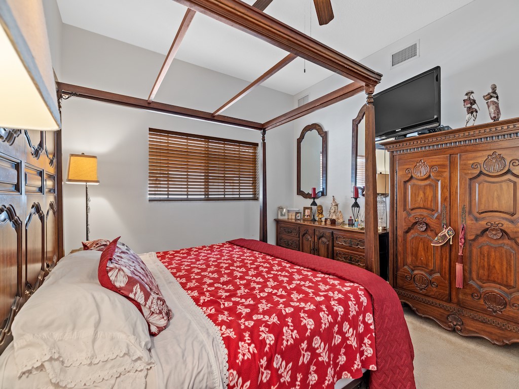 572 7th Square Southwest, Unit 101 Vero Beach, FL 32962 - Photo 21 of 34 a bedroom with a large bed and a flat tv screen on dresser