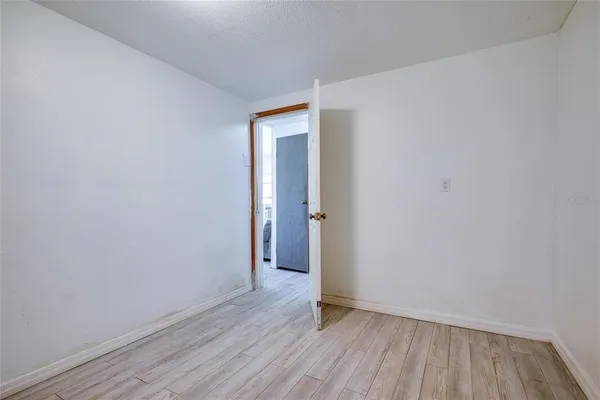 a view of an empty room with wooden floor and closet