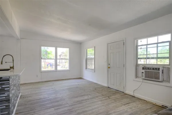 a view of an empty room with a window and wooden floor