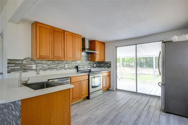 a kitchen with stainless steel appliances granite countertop wooden cabinets a stove a sink and dishwasher with wooden floor