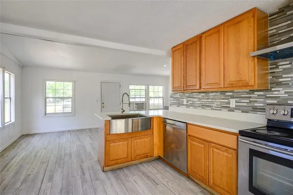 a kitchen with stainless steel appliances granite countertop wooden floors a stove and a window