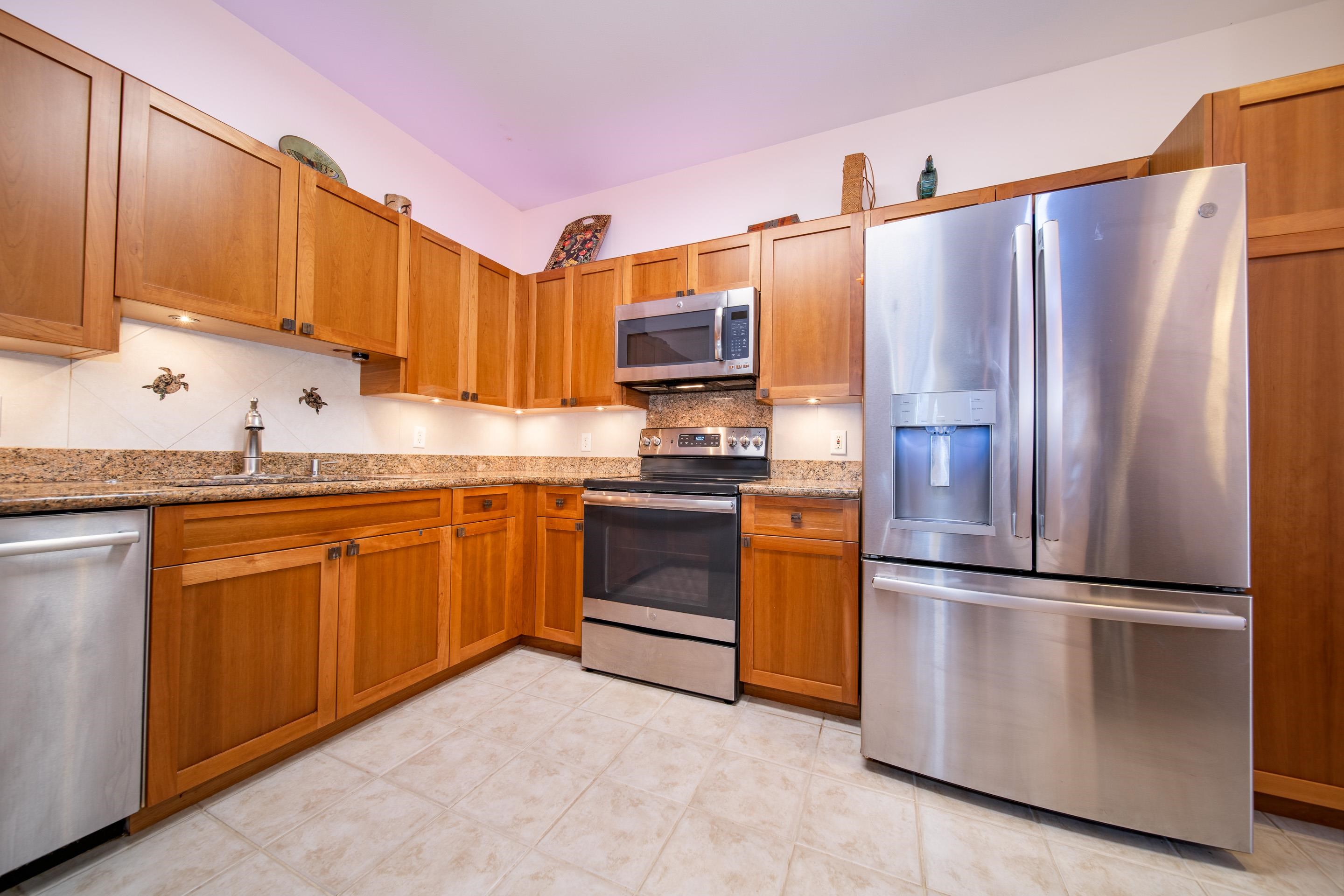 a kitchen with granite countertop stainless steel appliances a refrigerator a stove a sink and a cabinets