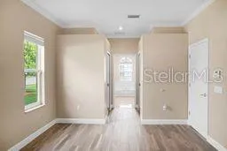 a view of hallway with window and wooden floor