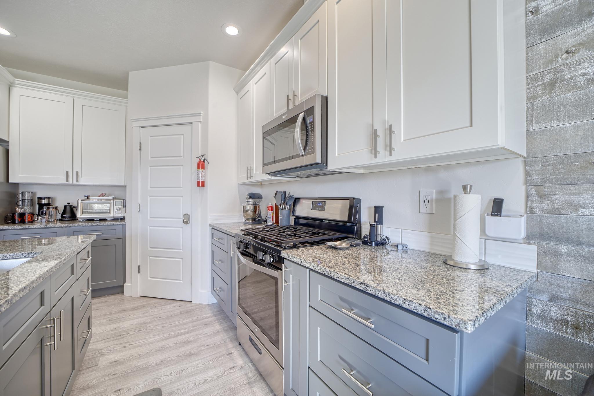 1087 Easy Avenue Twin Falls, ID 83301 - Photo 8 of 25 Kitchen featuring appliances with stainless steel finishes, white cabinetry, light stone countertops, light wood-style floors, and recessed lighting