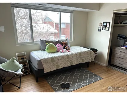 a bedroom with a bed a dresser and a large window