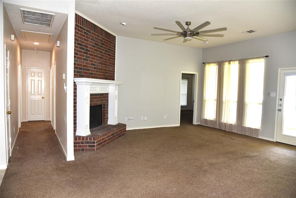 1526 Pebblestone Court Allen, TX 75002 - Photo 9 of 28 Spacious living area featuring a brick fireplace with a white mantel, brown carpet flooring, and a modern ceiling fan