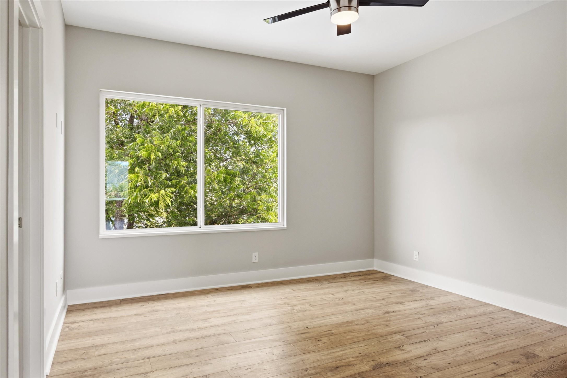 1210 Stobaugh Street, Unit B Austin, TX 78757 - Photo 9 of 40 Hardwood floors and a ceiling fan create a comfortable and inviting atmosphere in this sunlit room.