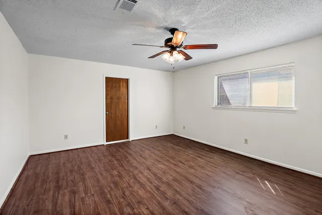 a view of an empty room with window and wooden floor