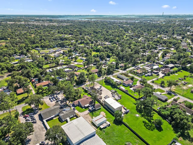 an aerial view of residential houses with outdoor space and trees