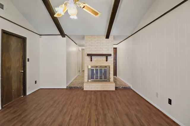 a view of an empty room with wooden floor and door
