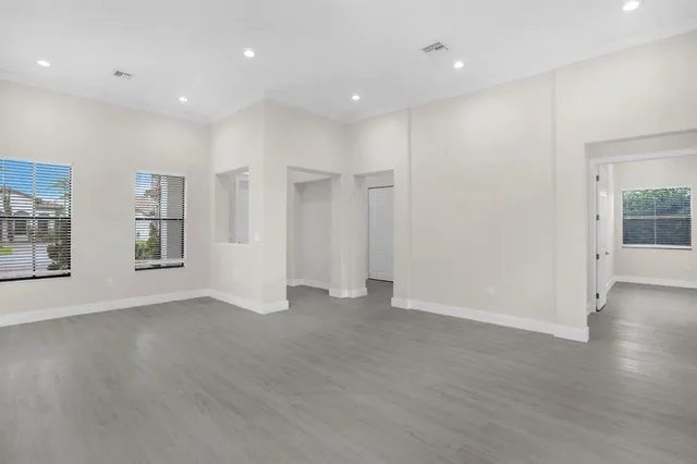 an empty room with wooden floor and windows