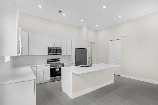 a large kitchen with cabinets stainless steel appliances and wooden floor