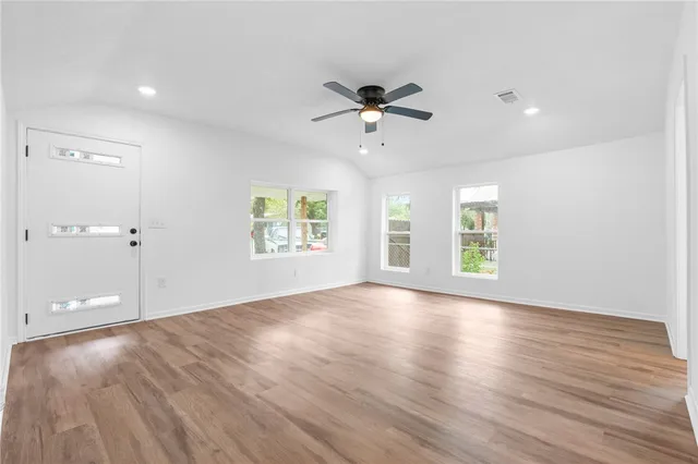 a view of an empty room with a window and wooden floor